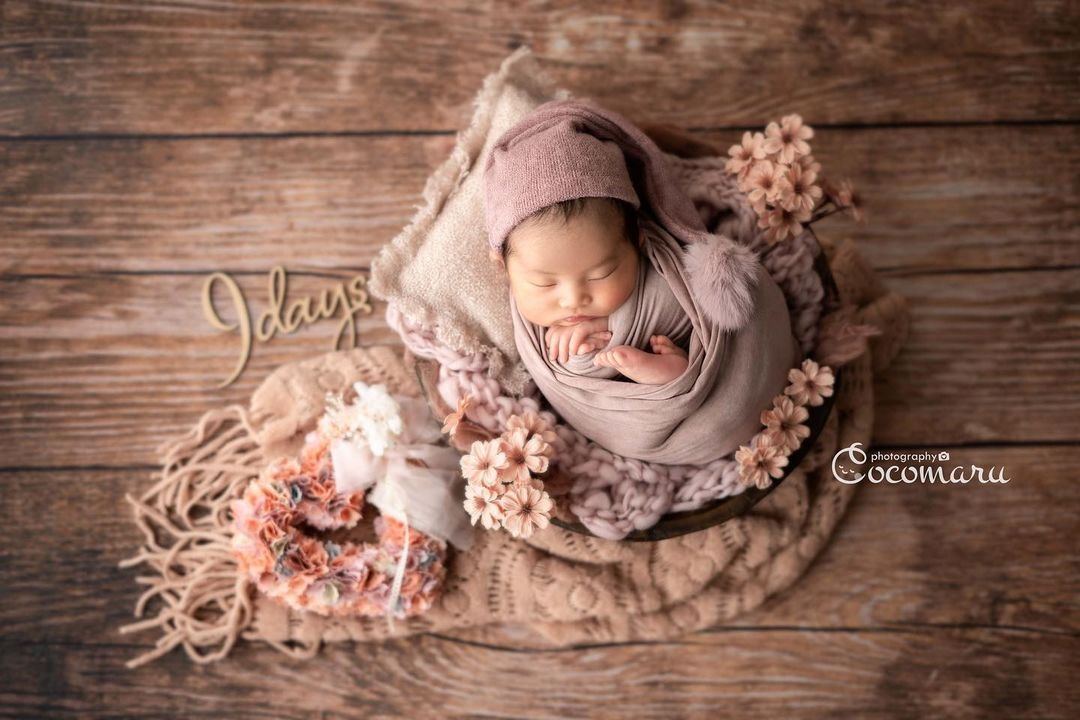 Baby lying on a wreath on a wooden floor