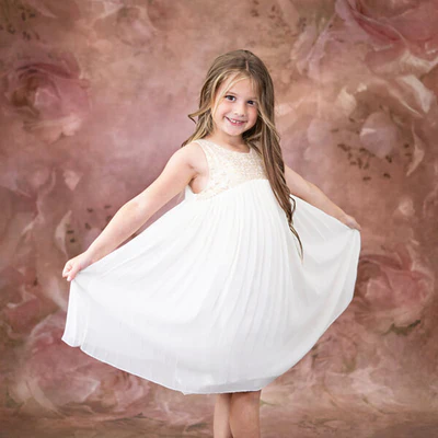 Girl in white dress standing in front of floral backdrop