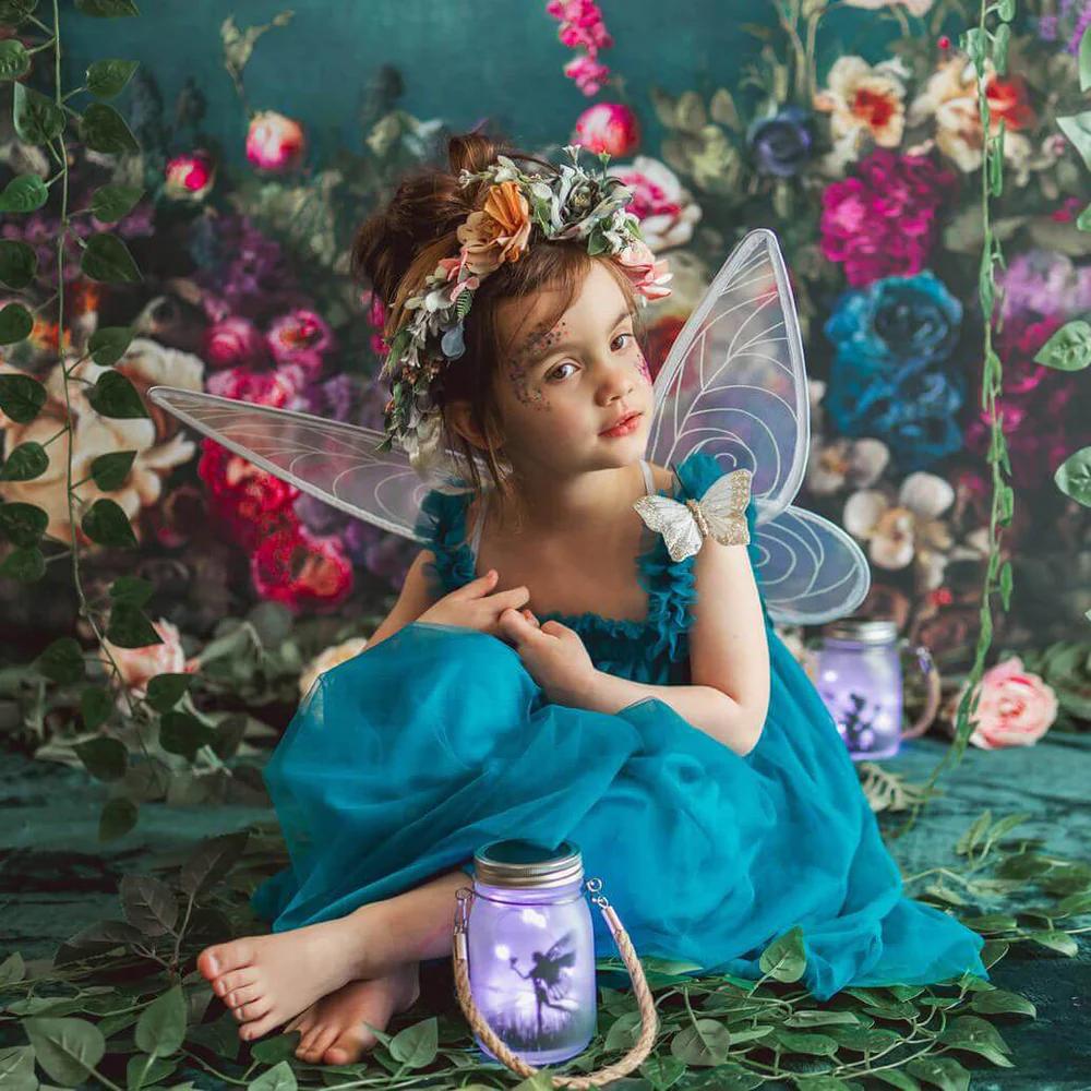 Girl with wings sitting in front of blue floral backdrop