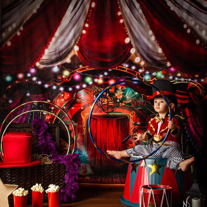 Boy holding circle prop in front of circus red backdrop