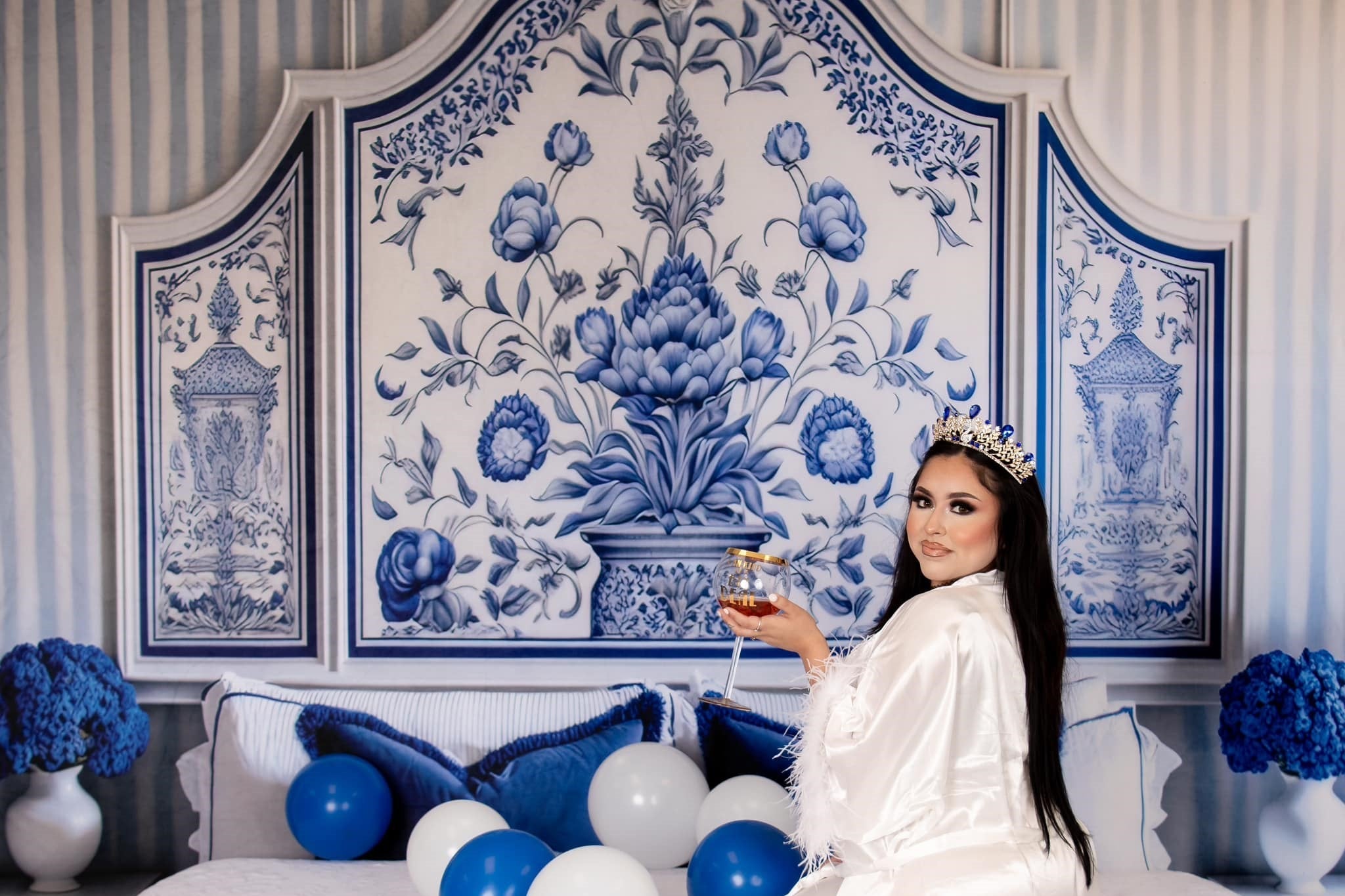 Woman with wine glass sitting on vintage bed in boudoir