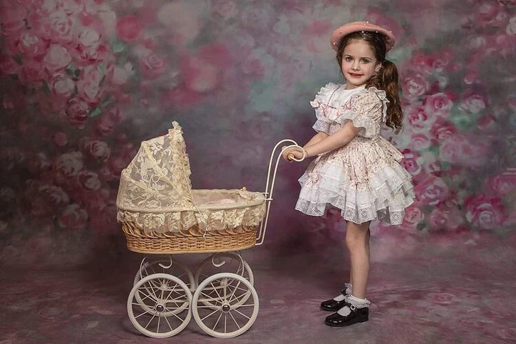 Girl pushing a baby stroller standing in front of artistic floral backdrop