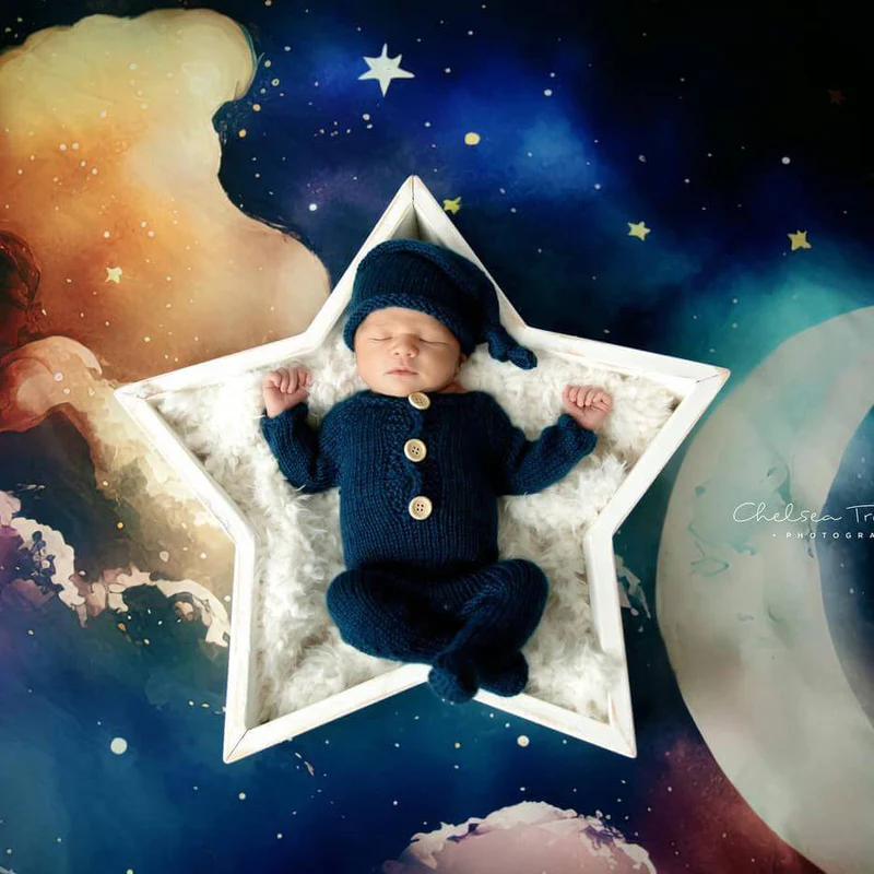 Baby lying inside star props in front of blue night sky with stars