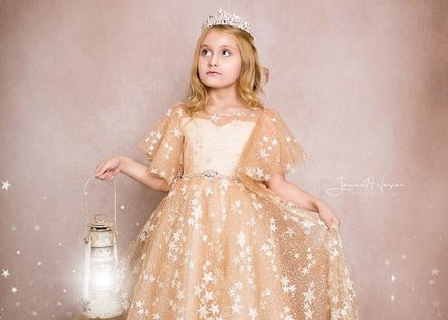Girl holding a lantern stands in front of a light pink backdrop