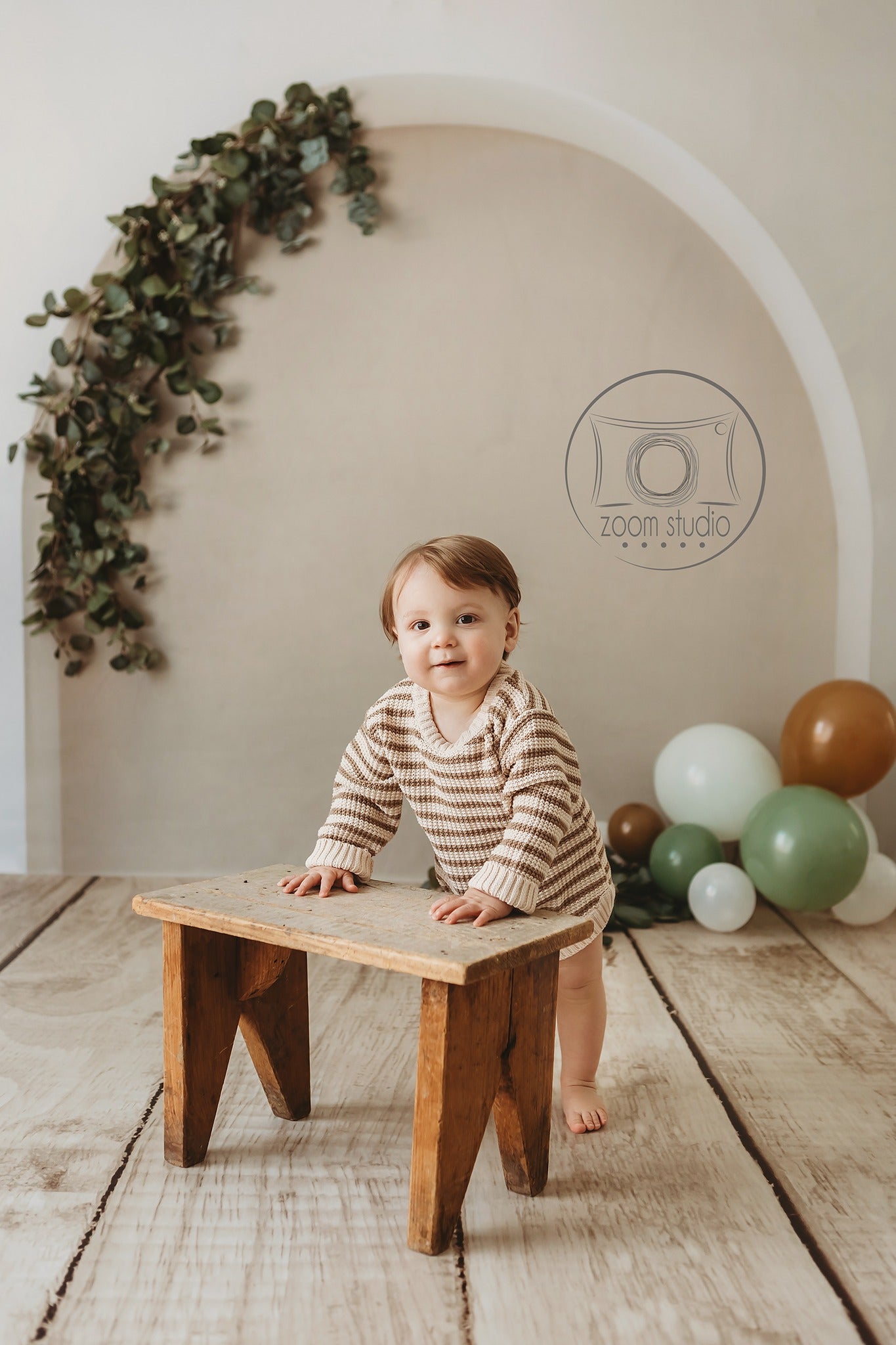 child holding stool standing in front of boho backdrop