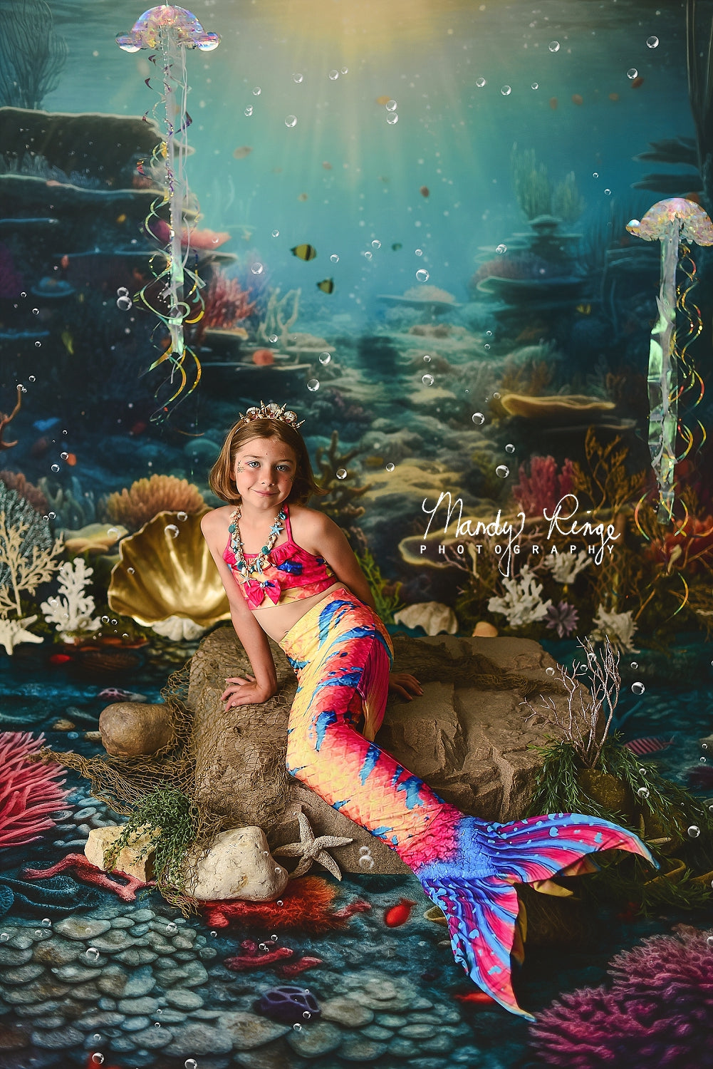 Girl dressed as a mermaid lying in front of the underwater world backdrop