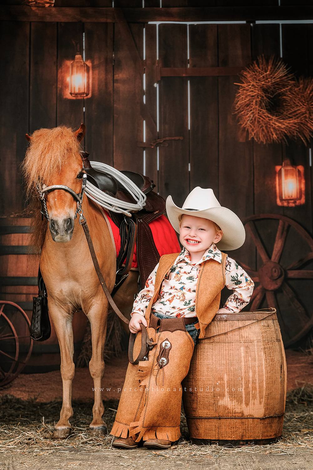 Little boy sitting with horse in front of autumn barn door backdrop