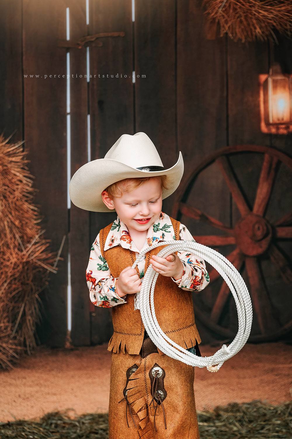 Little boy standing in front of autumn barn door backdrop