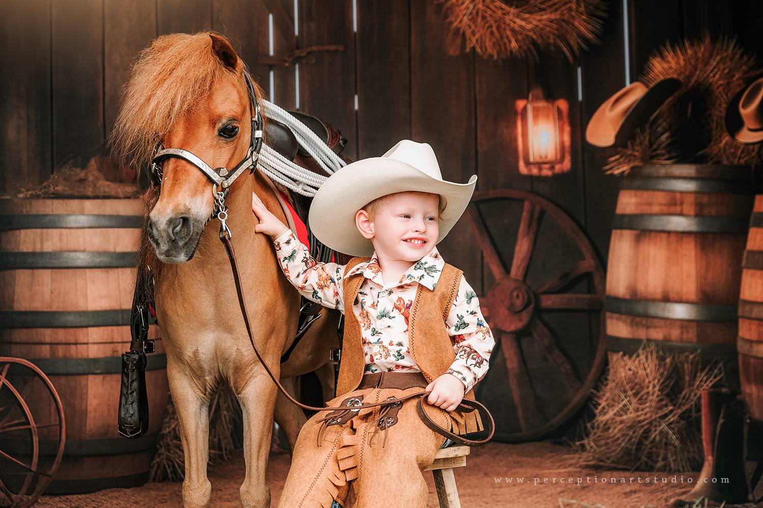 Little boy sitting with horse in front of autumn barn door backdrop