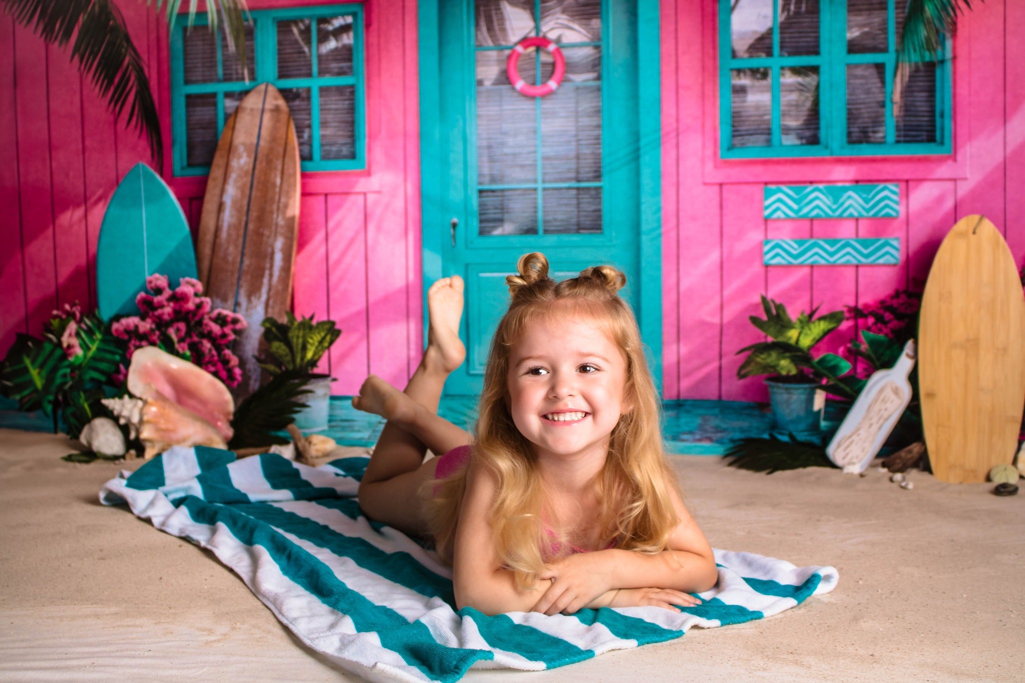 Girl lying on the beach in front of pink beach bar backdrop