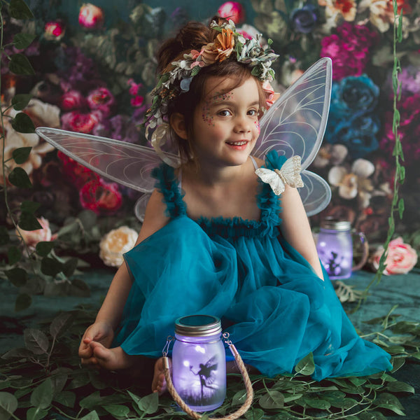 Little girl wearing wings sitting in front of Oil Painterly Floral Backdrop