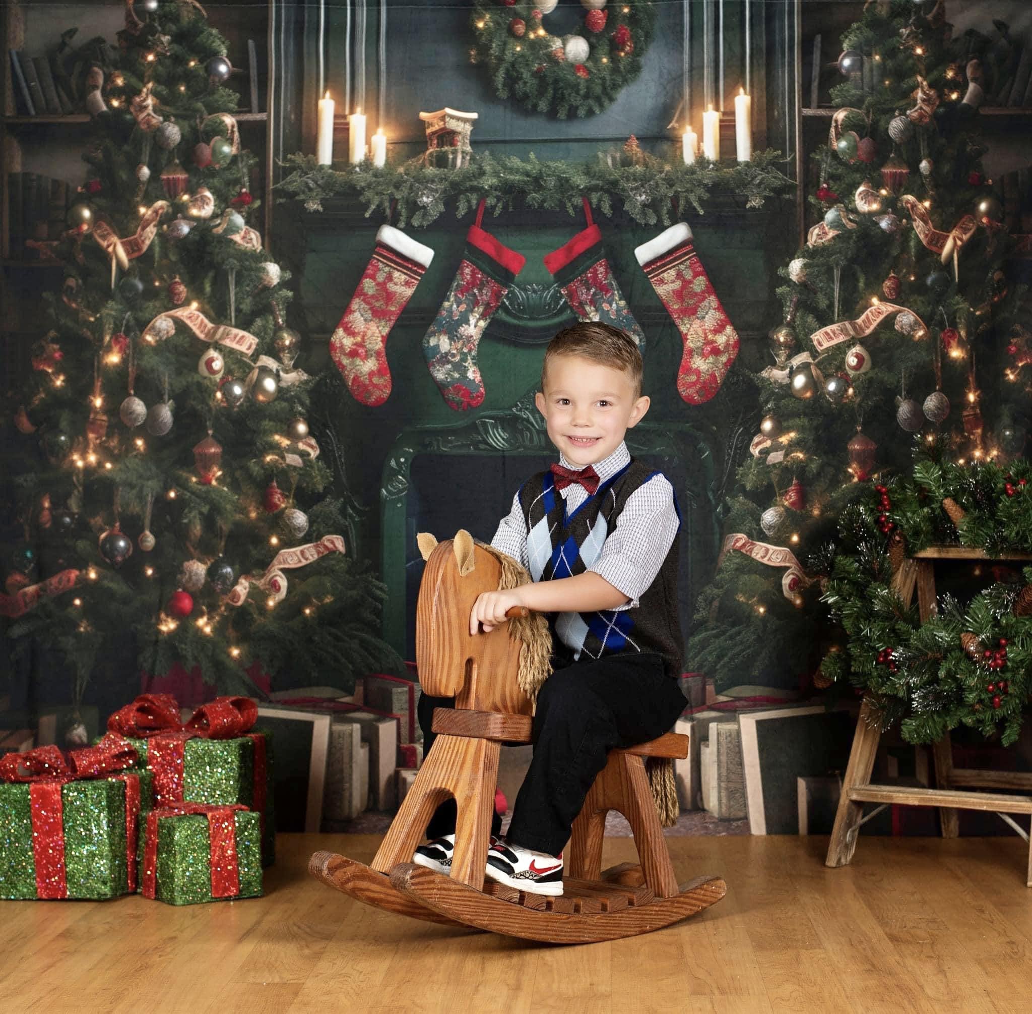 Boy riding a wooden horse in front of green Christmas fireplace backdrop