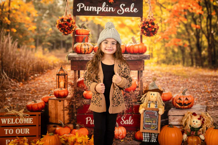 Girl in hat standing in front of autumn pumpkin sale backdrop