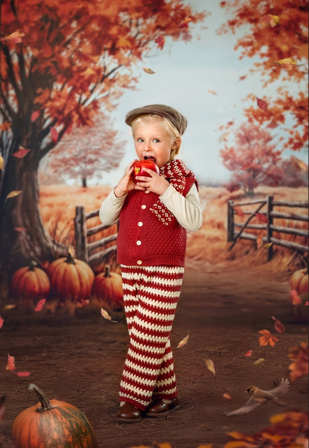 Boy holding red apple standing in front of autumn backdrop