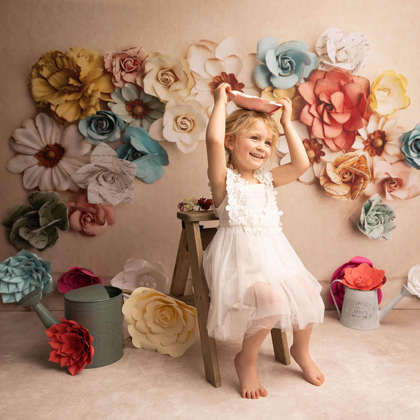 Girl holding a plate sits in front of a 3D flower backdrop wall