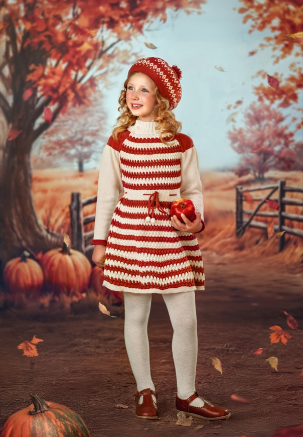 Girl holding red apple standing in front of autumn backdrop