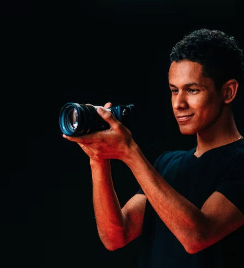 Man holding camera standing in front of black backdrop