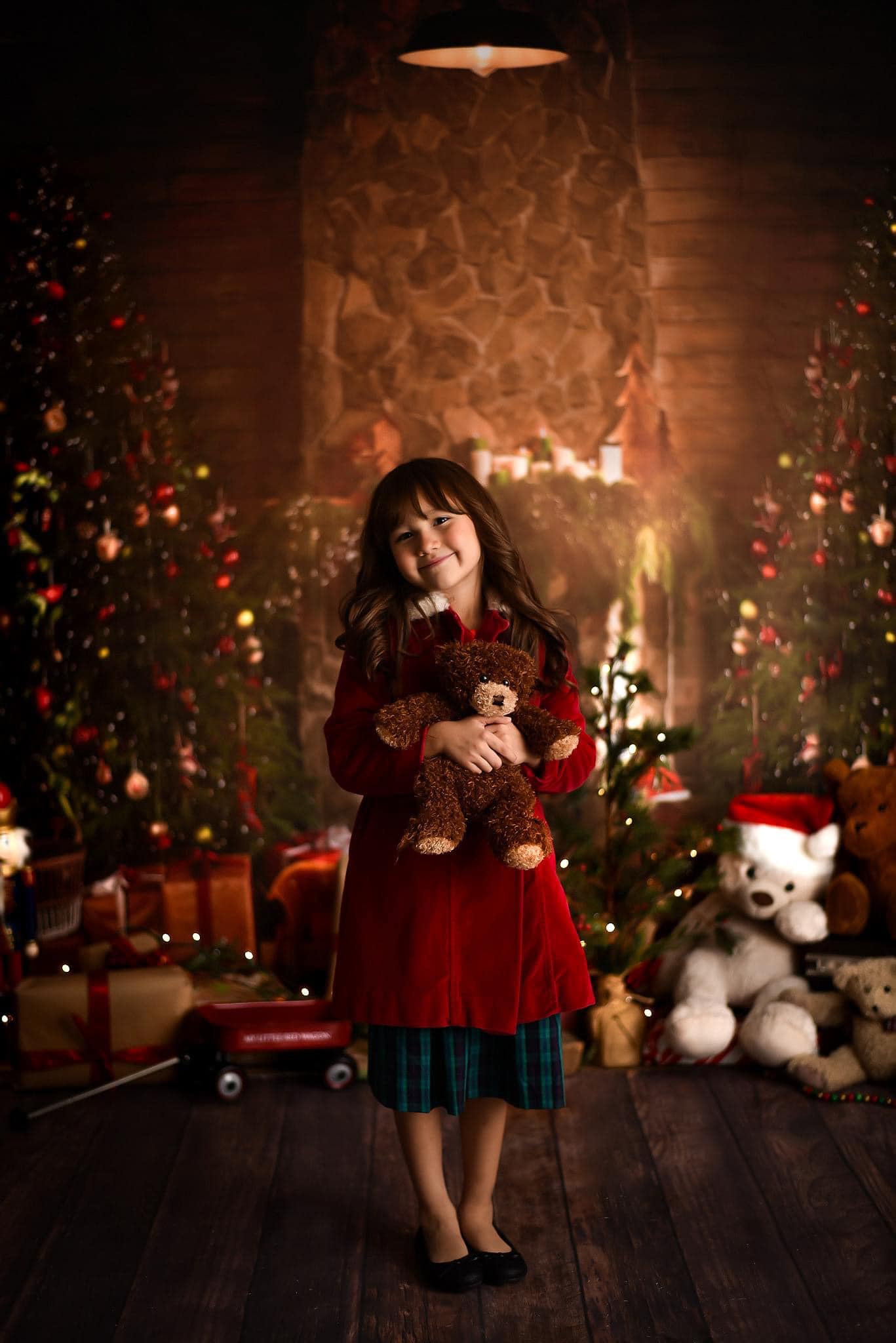 Girl holding teddy bear standing in front of Christmas Tree Fireplace Indoor Backdrop