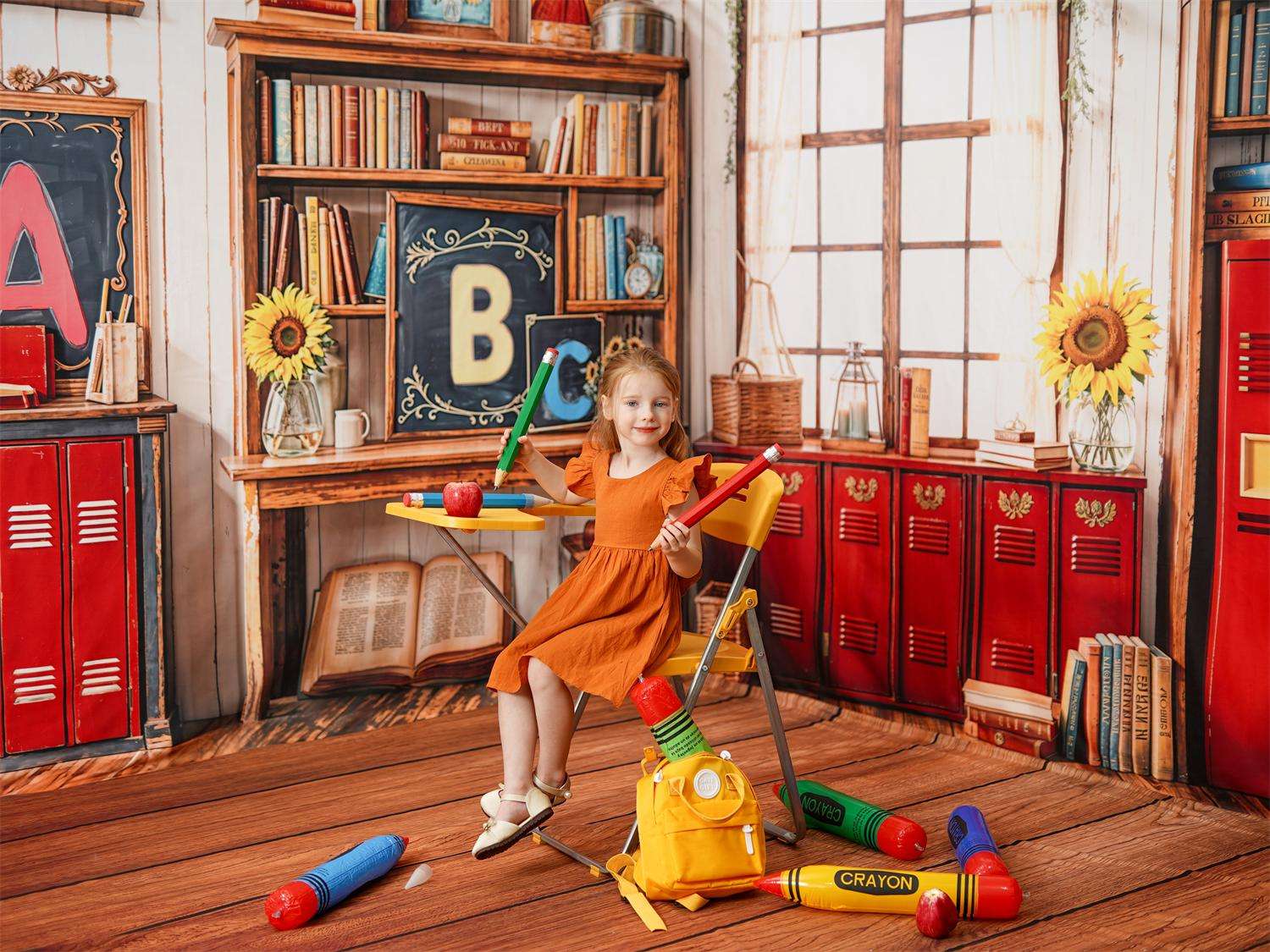 Girl in orange skirt sitting and writing in front of back to school backdrop