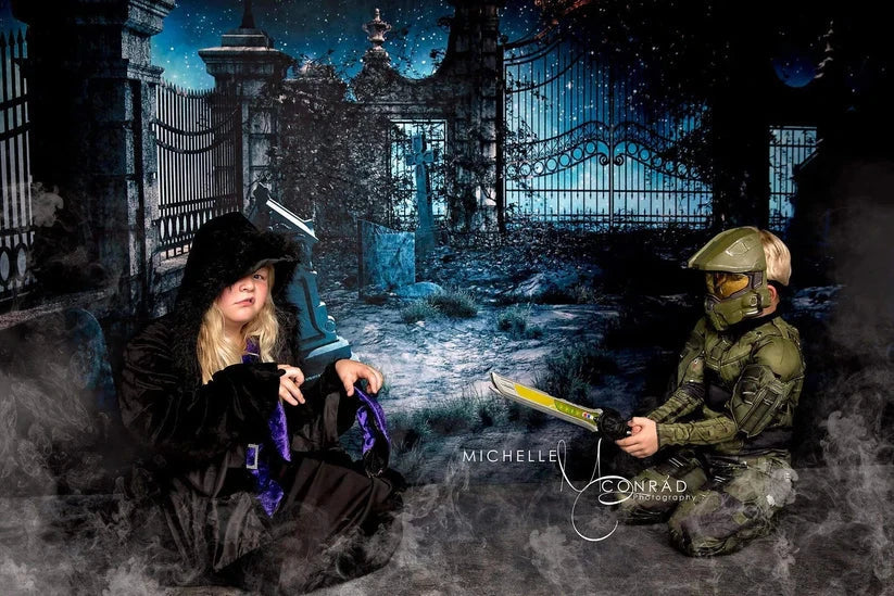 Girl and boy squatting in front of Halloween backdrop