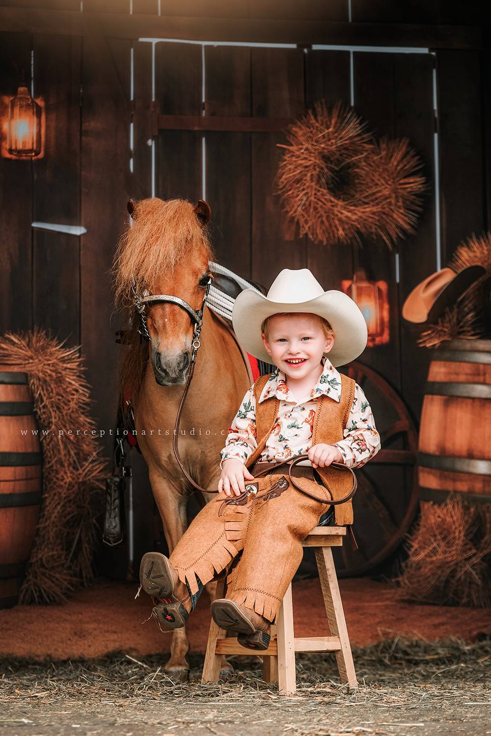Little boy sitting with horse in front of autumn barn door backdrop