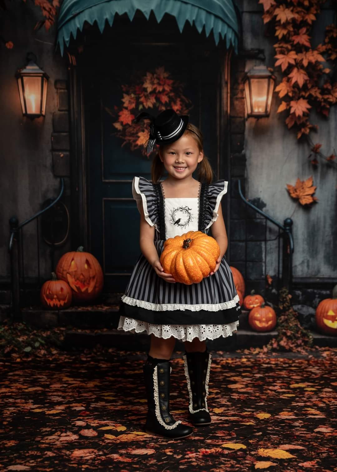 Little girl holding a pumpkin standing in front of Halloween fallen leaves background