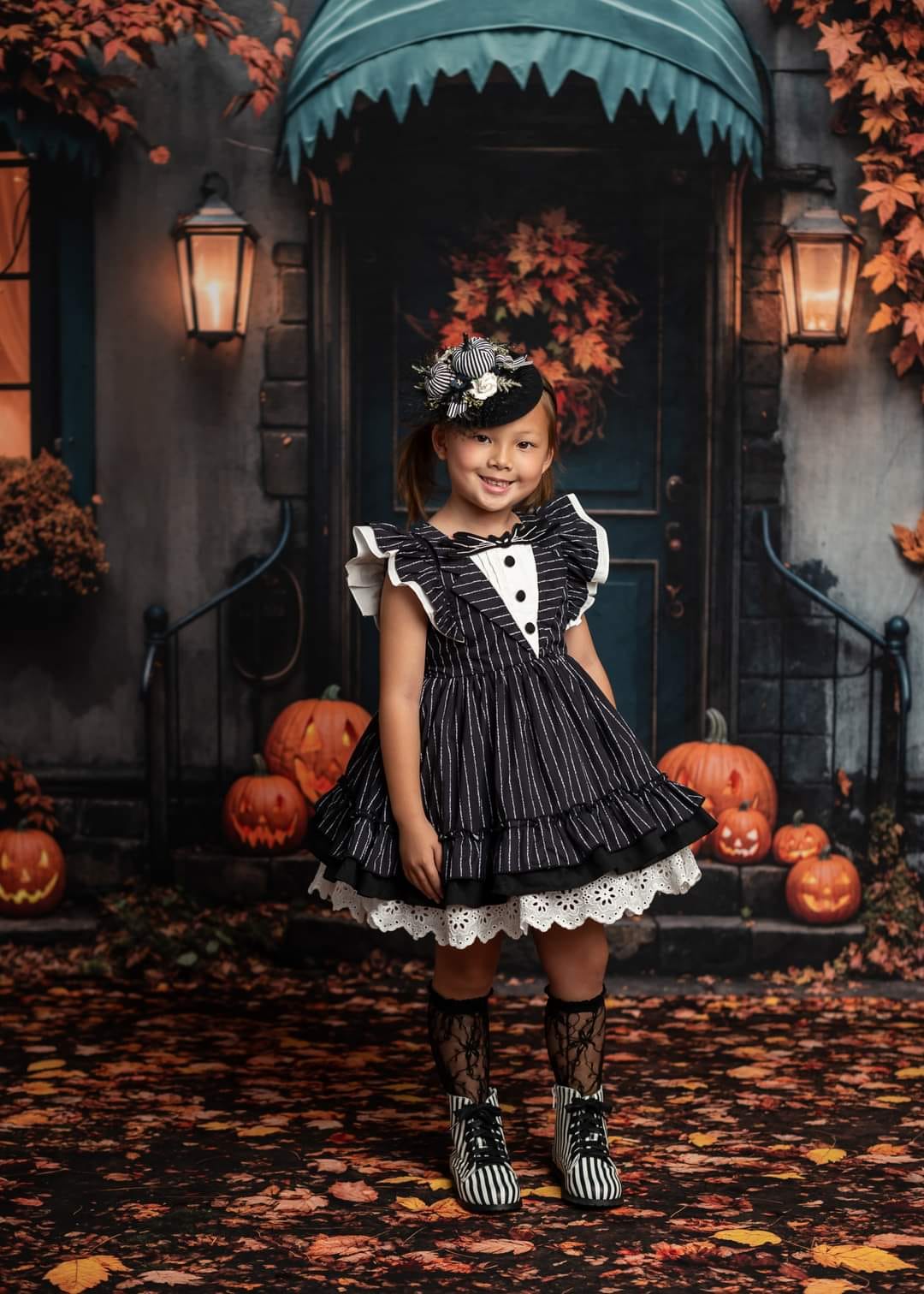 Little girl holding a pumpkin standing in front of Halloween fallen leaves background