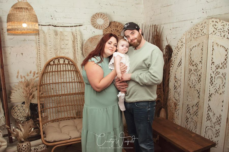 Dad and mom holding baby in front of Boho Macrame Wall Backdrop