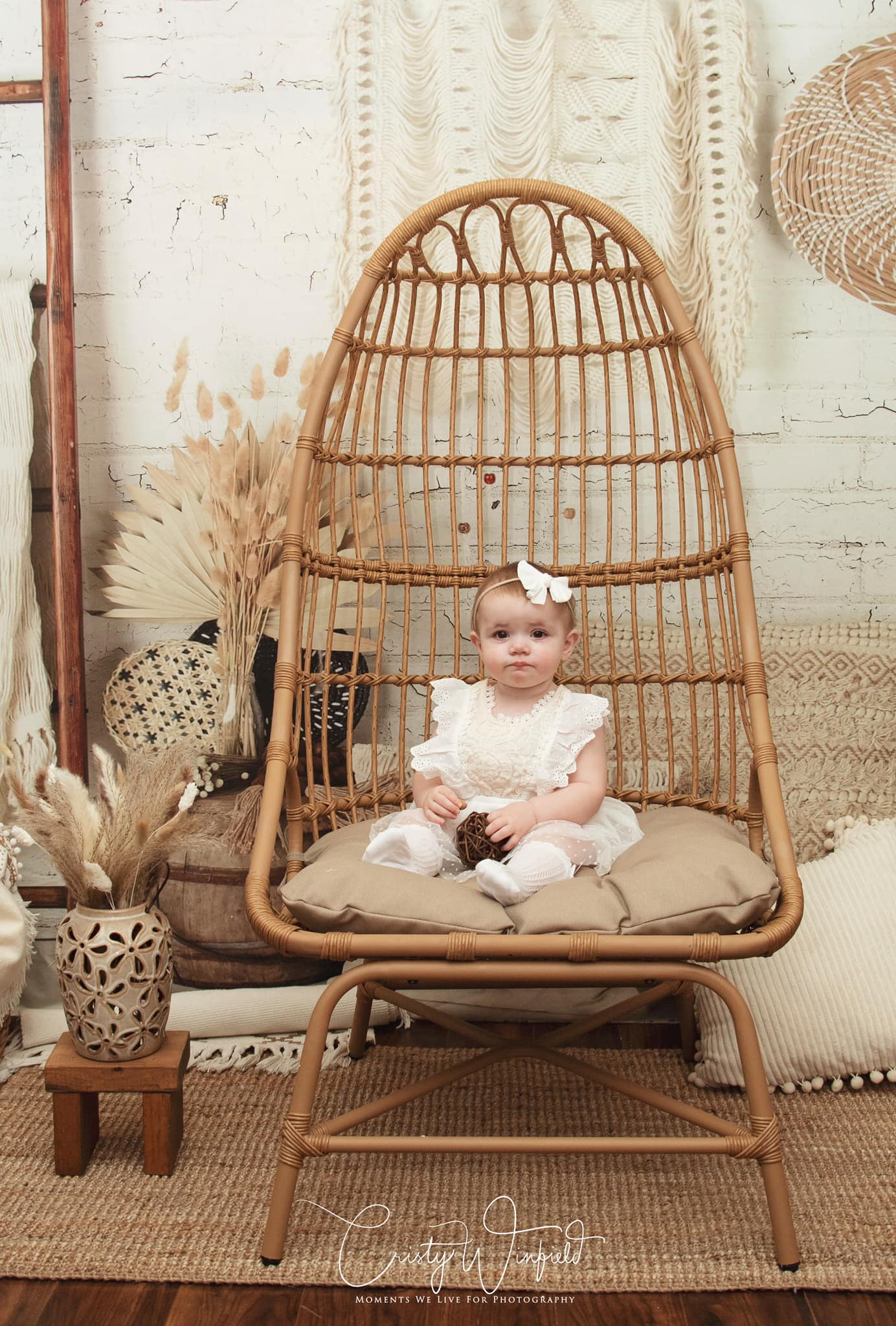 Little baby sitting on chair in front of Boho Macrame Wall Backdrop